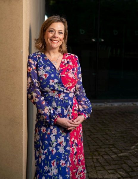 Woman in dress standing by wall