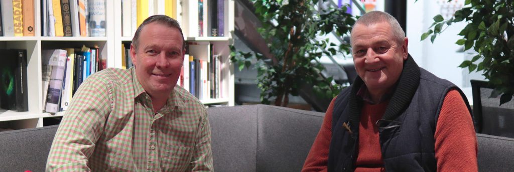 Two men smiling, sitting on a sofa