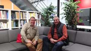 Two men smiling sitting on a sofa