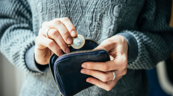 Person holding a wallet and inserting a two pound coin