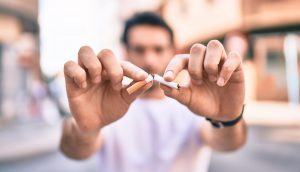 man breaking a cigarette in half with his two hands