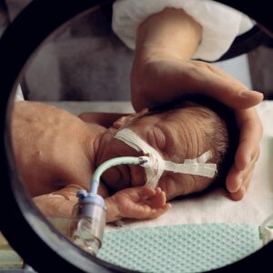 Newborn baby in intensive care wearing breathing apparatus