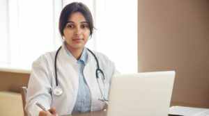Asian female doctor sitting at a desk in front of laptop
