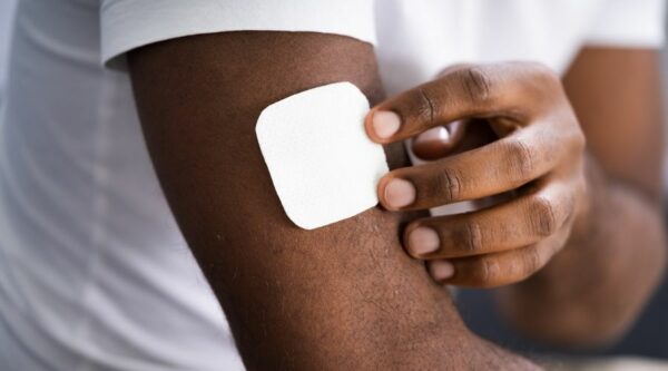 Man sticking a white nicotine patch on his arm